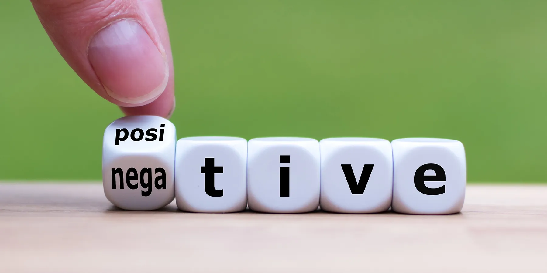 Photo of two fingers turning a dice, which changes the word from "negative" to "positive.”