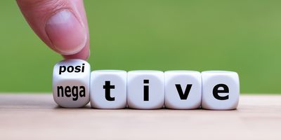 Photo of two fingers turning a dice, which changes the word from "negative" to "positive.”