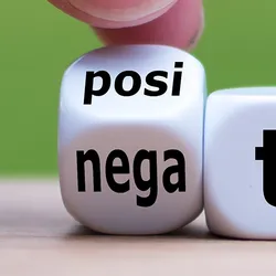 Photo of two fingers turning a dice, which changes the word from "negative" to "positive.”