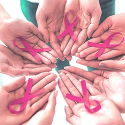 Photo of a circle of human hands holding pink breast cancer awareness ribbons in their palms.