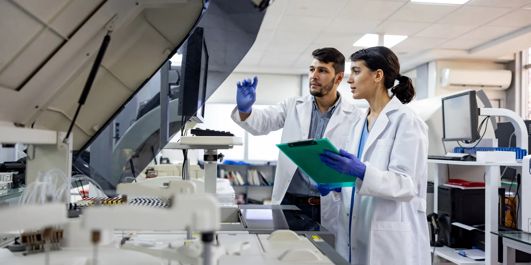 Photo of two laboratory scientists working at a flow cytometer in the clinical laboratory.