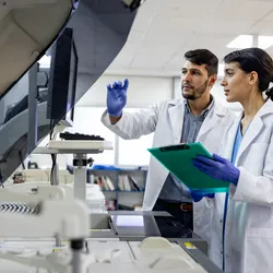 Photo of two laboratory scientists working at a flow cytometer in the clinical laboratory.
