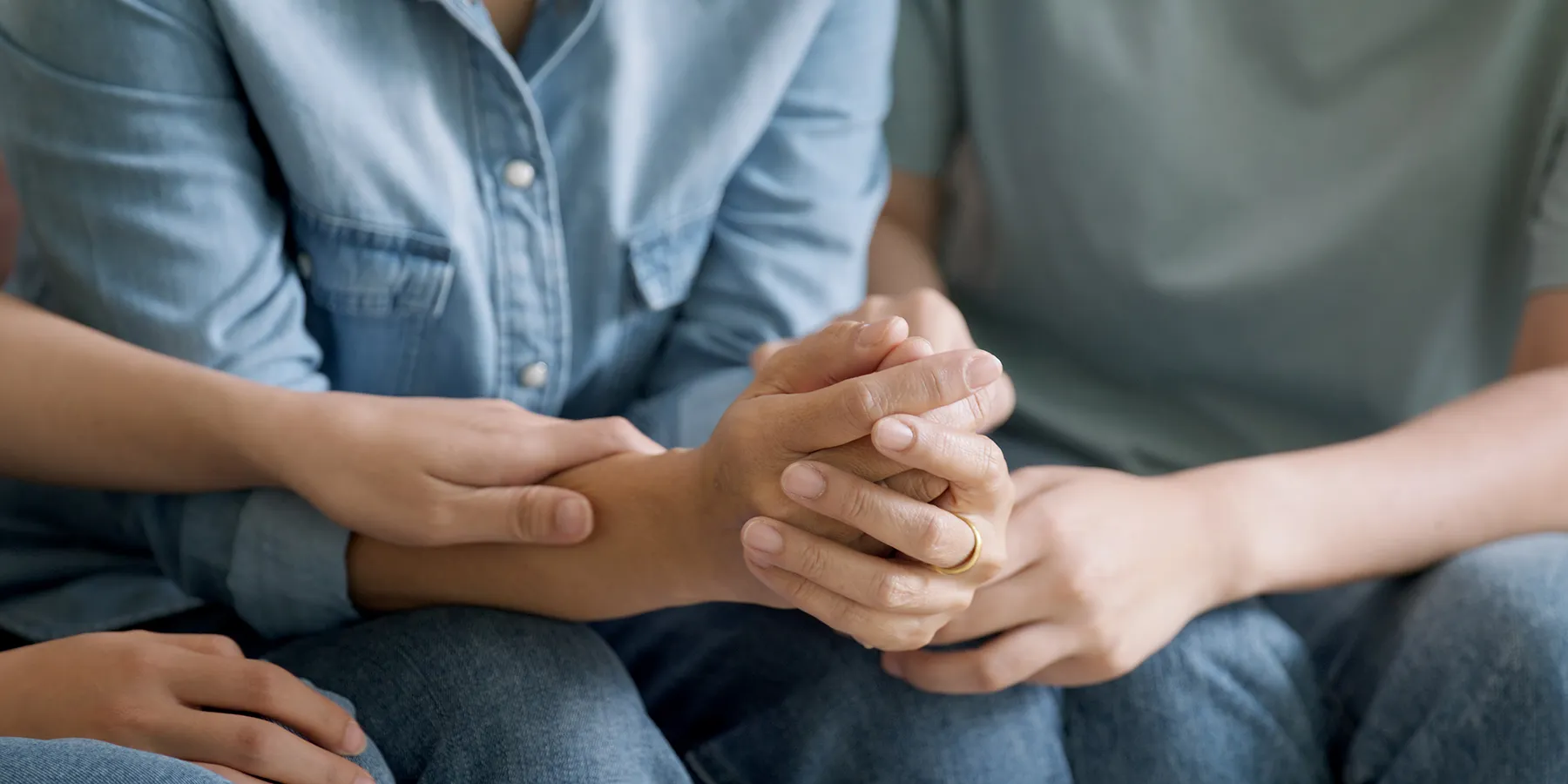 Photo of a person’s hands as they are comforted by another while they undergo a clinic visit for kidney transplant evaluation and testing.