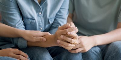 Photo of a person’s hands as they are comforted by another while they undergo a clinic visit for kidney transplant evaluation and testing.