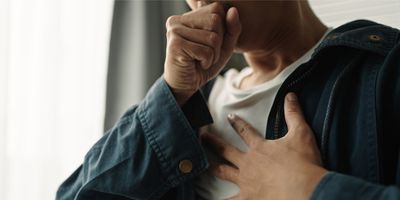 Photo of a person with a respiratory infection coughing into their closed fist.