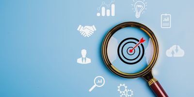 A magnifying glass focused on a target symbol with icons representing business development, strategy, implementation, lab testing, etc. around it on a blue background to represent an actionable strategy.
