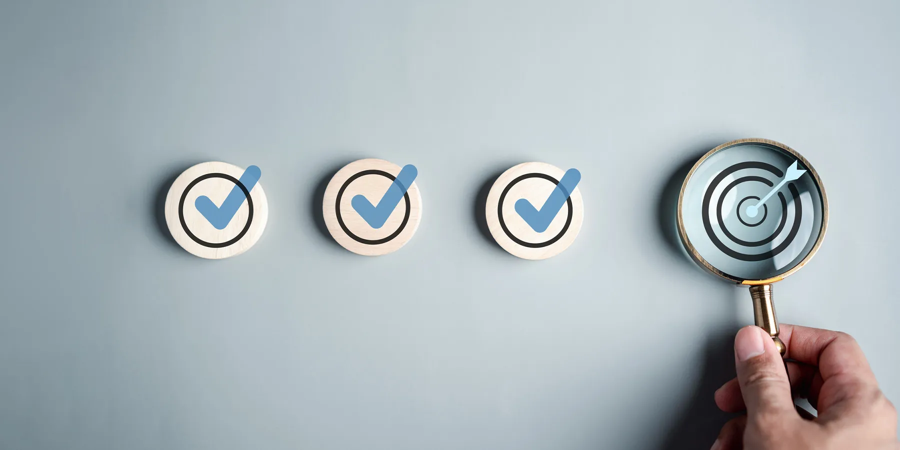 Photo of a person holding a magnifying glass over a target symbol to represent a checklist.