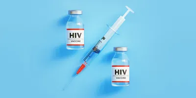 Photo of two HIV vaccine glass vials and a syringe against a light blue background.