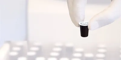 Gloved hand holding dry reagent cup