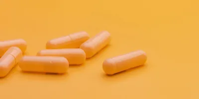 Image of antibiotics in the form of white pills against an orange background.