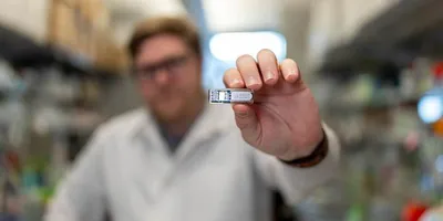 Rice University PhD student Chris Wright holds the implant, which uses cells to manufacture pharmaceutical drugs beneath the skin.